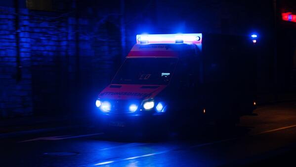Ein Rettungswagen fährt nachts mit Blaulicht auf einer Straße. (Symbolbild)